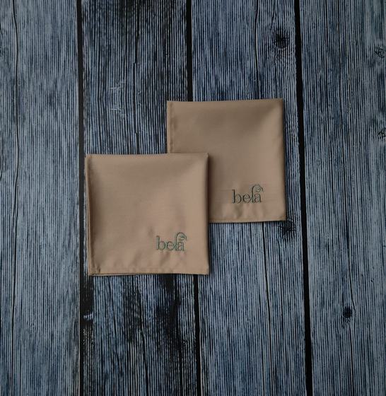 Beige table napkins with embroidered logo, folded pair, custom made by RestroCart, New Delhi
