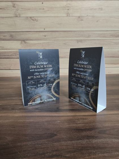 Dark teal tent cards with printed offer details on wooden floor, custom made by RestroCart, New Delhi